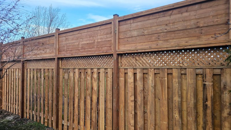 A stained cedar privacy fence with a lattice-top detail, built by The Picket Fence Co. in Milton